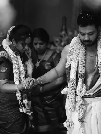 A solemn, beautiful moment from a Hindu ceremony, captured in black and white. The couple holds hands, their focus on the ritual, showcasing the gravity and sanctity of their vows.