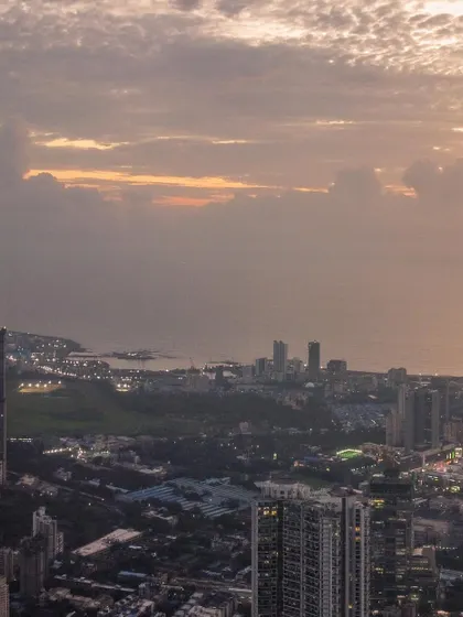 A detailed shot of the Mumbai coastline and Malabar Hill area, seen from a high altitude under a textured sky.