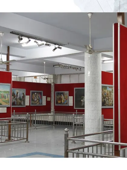 A wide view of an exhibition hall inside the Bhai Mati Das Museum. The displays, featuring history paintings against vibrant red walls, create a distinct visual narrative that I critically examine in my work on Sikh museology.