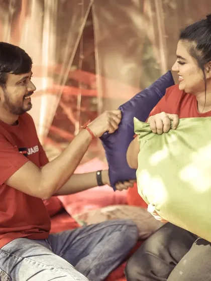 A playful pillow fight scene from a pre-wedding shoot, perfect for capturing the fun and lighter side of a couple's relationship.
