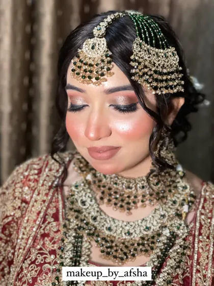A close-up of another beautiful bride. The contrast between her dark hair, red and gold outfit, and the green jewellery is absolutely striking. The makeup is glamorous with a nude lip to balance the look.