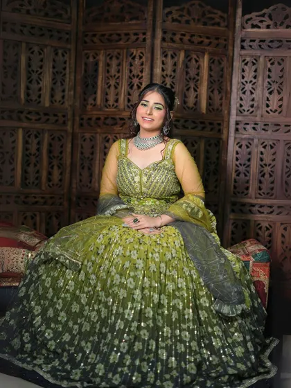 A seated portrait in the green and yellow floral lehenga, showing its beautiful volume and sparkle.