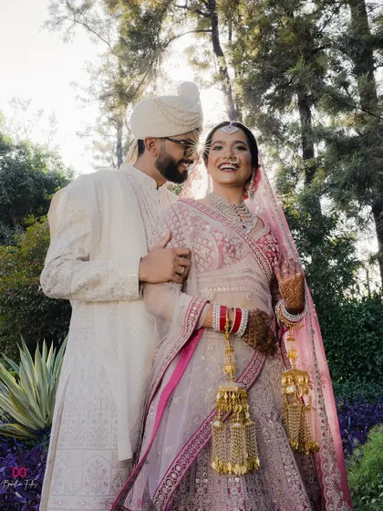 A joyful portrait of the couple, with the bride's radiant smile lighting up the frame, captured in a beautiful garden setting on their wedding day.