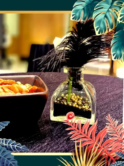 A small but striking decor piece, using a black feather and gold beads in a glass bottle to complement a glamorous theme.