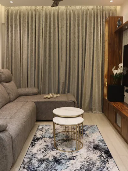 A comfortable living room setup with a recliner sofa and a wooden TV unit. The abstract rug and nested center tables add a modern touch to the cozy space.