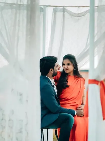A romantic pre-wedding photo with a couple framed by soft white curtains, creating a dreamy and ethereal mood.