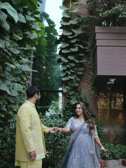 A candid moment between a couple at their wedding, set against a stunning wall of green foliage.