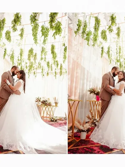 A romantic portrait of the bride and groom under a canopy of hanging greenery. The long train of her dress adds a touch of drama and elegance.