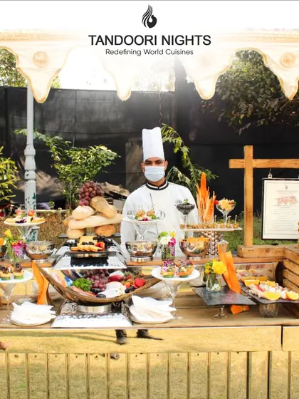 An outdoor event setup featuring a beautiful grazing table. Our chef stands ready to assist guests, ensuring a personalized and high-end service experience amidst a rustic, chic ambiance.