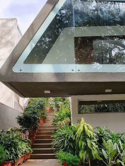 A close-up of the cantilevered corner of the Mobius Home. This view shows the seamless integration of the glass and concrete structure, flanked by a staircase garden that enhances the connection to the landscape.