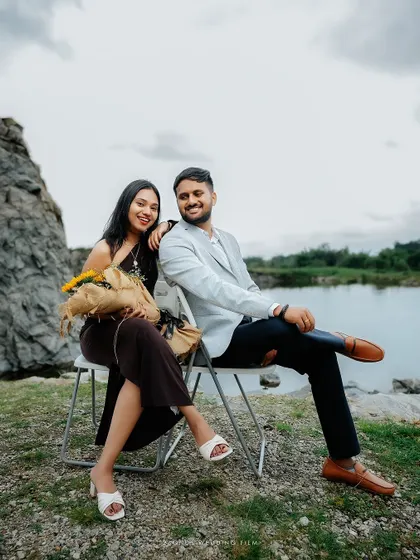 A relaxed portrait of the couple seated by a quarry, the bride holding sunflowers, capturing a serene and happy moment in a rugged natural environment.