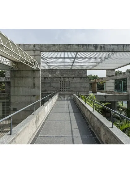 An elevated bridge connects different parts of the sports complex, passing over green spaces and offering views of the surrounding campus.
