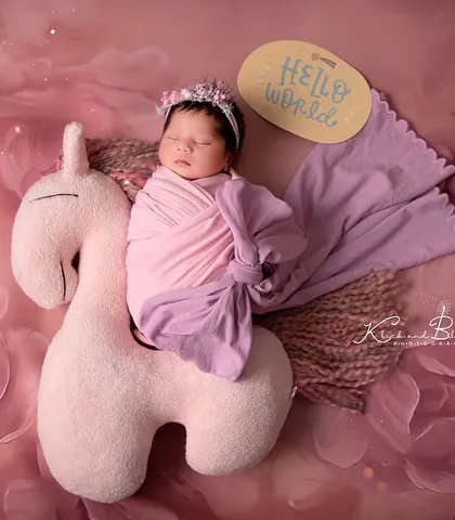Hello, world! This little unicorn rider is ready for a magical adventure. The soft, floral digital backdrop adds an extra layer of enchantment to the scene.