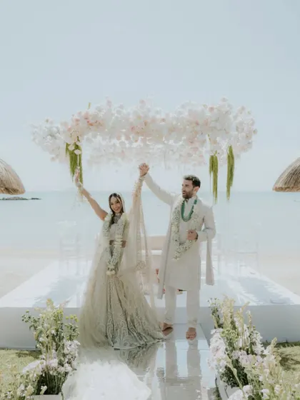 The couple celebrating under their floral mandap after the ceremony in Mauritius. This wide shot, featured in Vogue India, showcases the beautiful beachside setting and the happiness of the newlyweds.
