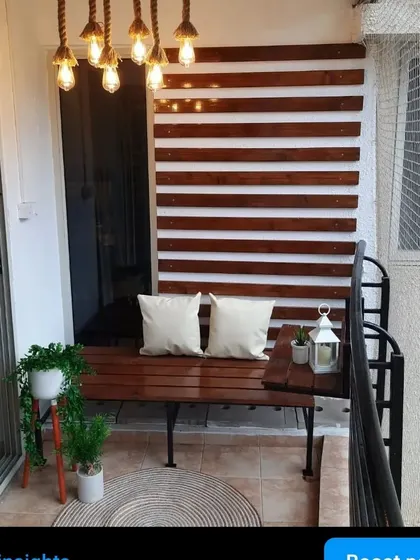 A full view of this cozy and modern balcony. The custom pinewood bench is paired with matching wall slats and beautiful rope lighting for a complete look.