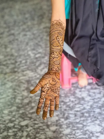 A full-length view of a single arm adorned with bridal henna, showcasing the seamless flow of the design from wrist to elbow.