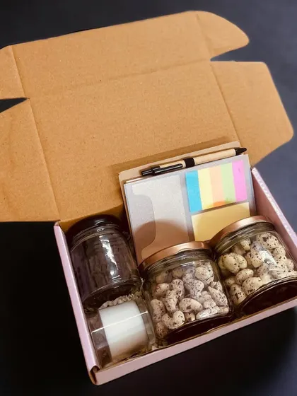 This budget-friendly corporate gift box includes three jars for nuts or snacks, a notebook with a pen, and a candle, offering great utility and a personal touch.