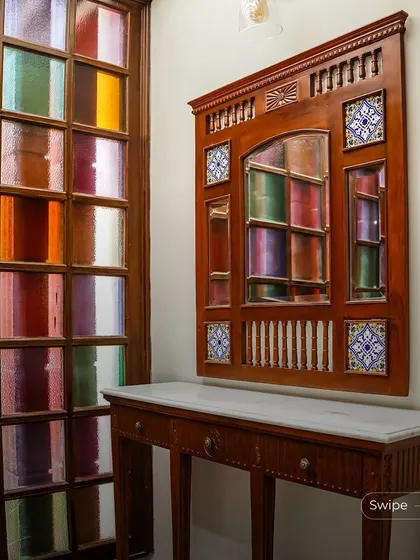 This unique entryway features a console table and a decorative mirror set against a wall of colorful stained glass. It’s a playful and artistic touch that makes a memorable first impression.