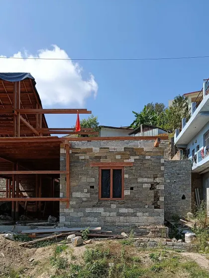 **Market Plaza, Champawat:** Construction photo of a market plaza in Uttarakhand. The project uses a combination of local stone for the base and a wooden frame structure, reflecting the regional building traditions.