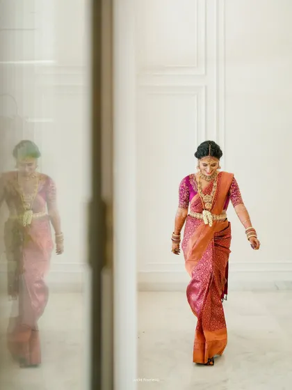 A full-length shot of the bride walking, her reflection captured in the glass, creating an elegant and artistic portrait.