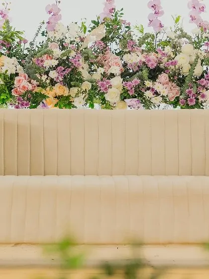 A modern beige sofa set against a wall of pastel flowers, showcasing our curated furniture choices.