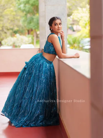 The model posing by a window in the teal lehenga, showing how the fabric catches the light.
