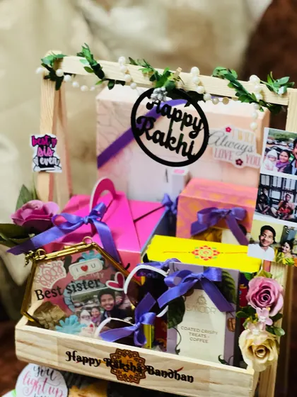A close-up on the personalized details of the sister's Rakhi hamper, including a custom frame and photos.