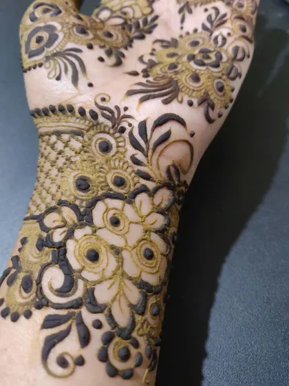A close-up of the wrist area, showing detailed floral work with bold outlines and delicate shading.