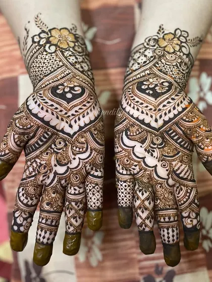This design uses bold negative space to create a heart shape on the back of the hand, filled with delicate patterns.