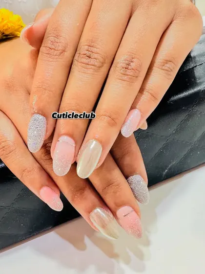 A neutral yet glamorous set featuring a mix of pink, nude, and silver glitter nails in different textures.