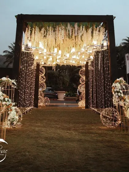 A closer look at the details. This entrance combines hanging chandeliers, cascading white flowers, and thousands of fairy lights to create a dense, sparkling canopy that feels utterly magical.