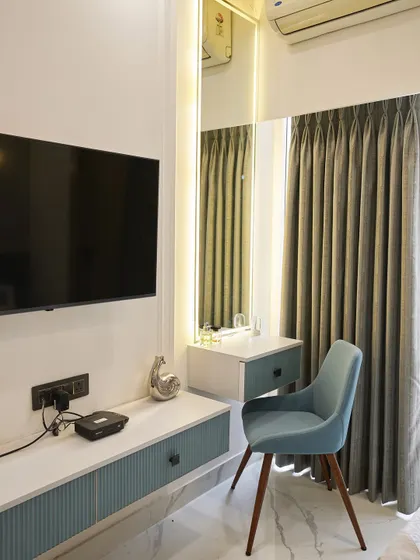 A compact and functional vanity and TV unit combo. The floating design keeps the floor clear, making the room feel more spacious. The pop of blue on the chair adds a playful touch.