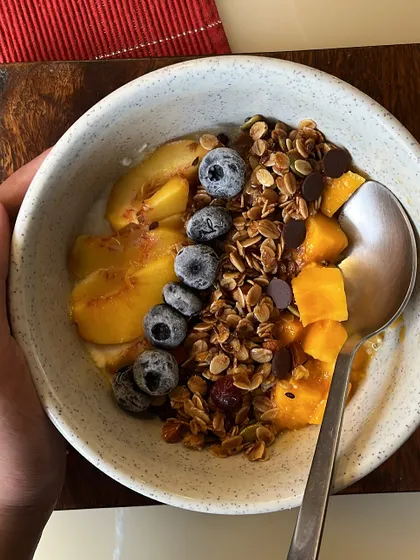 Start your day with a bowl of pure goodness. Our handmade granola, packed with fiber, good fats, and protein, is shown here served with yogurt and fresh fruit for a wholesome and delicious breakfast.