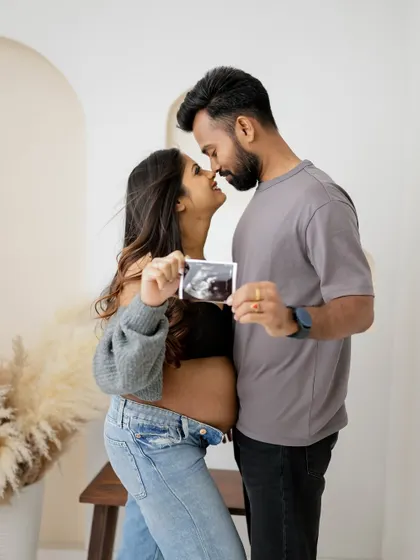 A close-up, intimate portrait of a couple holding their sonogram picture. The focus is on their connection and the beginning of their family story.