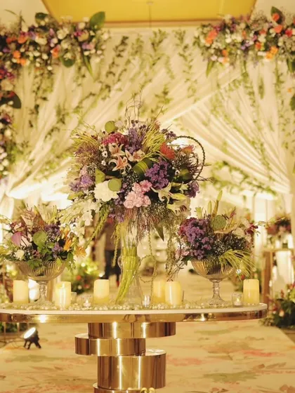 A grand floral tablescape set against a beautifully draped backdrop. This setup combines lush flowers and candlelight to create a luxurious focal point for the celebration.