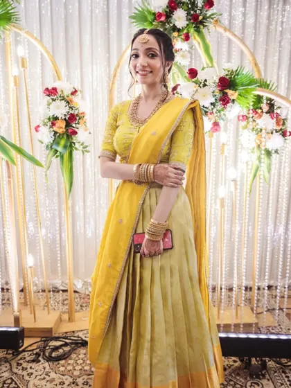 A bright and sunny look for a wedding guest. The soft, natural makeup enhances her features beautifully, pairing perfectly with her yellow lehenga and the festive atmosphere.