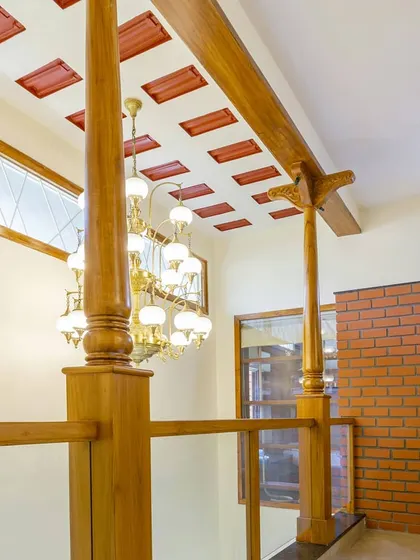 In this contemporary Indian home, I used traditional wooden columns and a filler slab ceiling to create a sense of heritage and volume. The grand chandelier adds a touch of elegance to the double-height space.