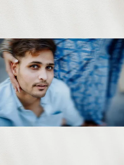 An artistic, close-up shot focusing on the groom's eyes as the bride's hand gently caresses his face.