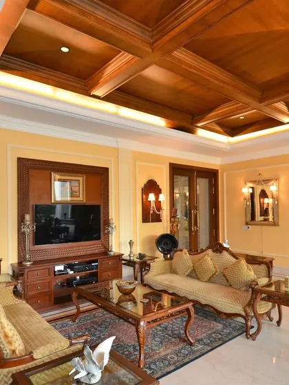 A grand, classical room featuring a coffered wooden ceiling and ornate, hand-carved furniture. This project showcases our expertise in traditional craftsmanship, from the detailed furniture to the custom moldings and wall treatments.