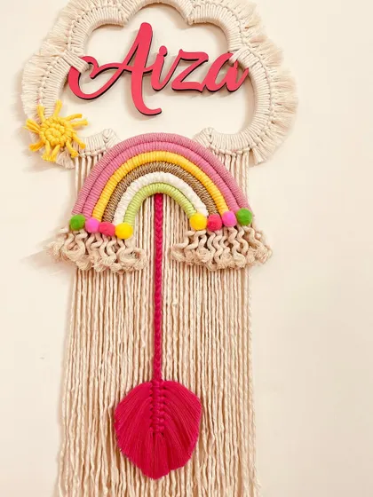 A pink-themed rainbow dreamcatcher for 'Aiza'. The bright pink leaf adds a beautiful pop of color to this personalized nursery wall hanging.