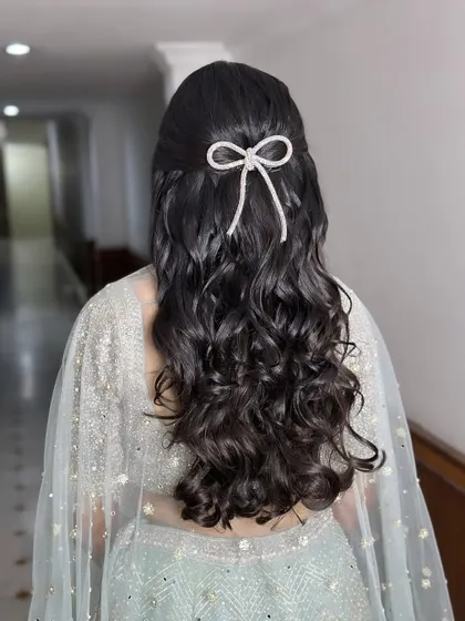 Adding a touch of elegance with a simple bow. This half-up hairstyle with soft waves is made special with a beautiful rhinestone bow accessory, perfect for a Roka or Engagement.