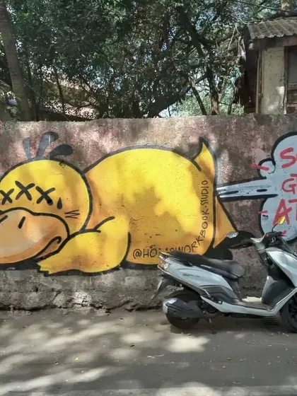 A humorous piece of graffiti in Bandra featuring a knocked-out yellow duck. The speech bubble "Sorry to grab your attention" adds a layer of wit to the cartoonish art.