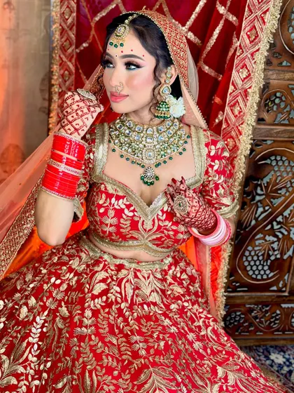 A close-up portrait. The green bindi and jewelry add a beautiful contrast to the red outfit.