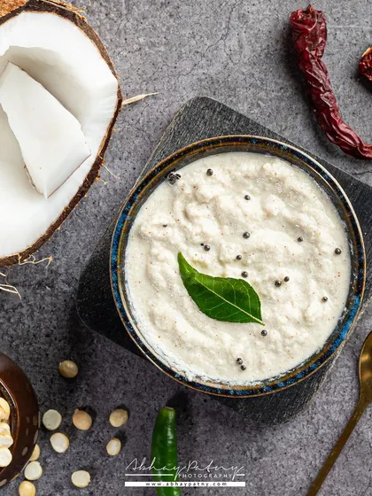 A top-down shot of fresh coconut chutney. The composition includes the core ingredients like coconut and chillies, which tells a story of freshness and authentic preparation.