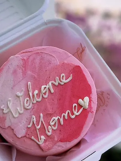 A simple and sweet "Welcome Home" bento cake with a pink watercolor effect. It's the perfect little treat to greet a loved one.