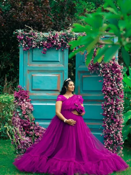 This beautiful purple gown looks stunning against the floral backdrop, making it a perfect choice for a garden-themed maternity shoot.
