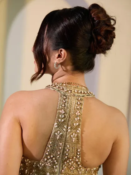 A detailed shot of the messy high bun, showcasing the texture and placement. This style is designed to look beautiful from every angle, a crucial element for event hairstyling.