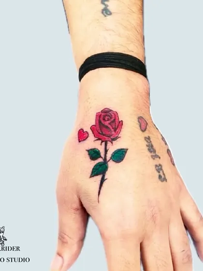 A small color rose tattoo on the hand, used here to cover faded script. This demonstrates how even a small, colorful design can be an effective cover-up solution.