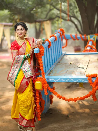 A playful moment during a pre-wedding shoot. The bride looks radiant in her Nauvari, posing against a decorated bullock cart, which adds a traditional, rustic charm.