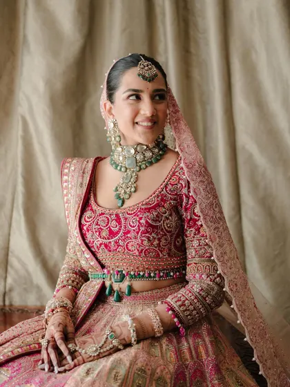 A happy, smiling bride. This close-up captures her joyful expression and the stunning details of her Tarun Tahiliani outfit and emerald jewelry.